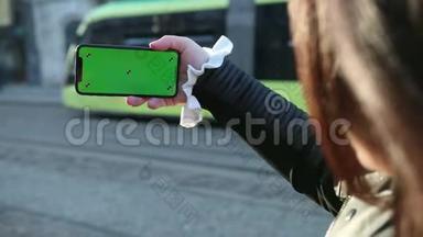 女孩在智能手机上说话，手机的绿色屏幕。 向屏幕上看到的人挥手